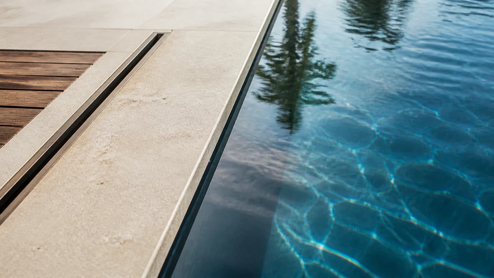 Close study of limestone coping, blue water, cedar, and bronze-toned detailing